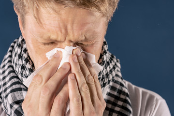 Man with cold and flu illness suffering from a headache and cough. Blue background
