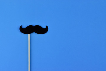 Black mustaches on light blue background representing an annual event involving the growing of...
