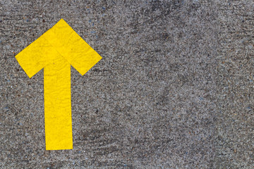 D.I.Y. yellow up arrow symbol builds by pike leak seal tape shown on old concrete floor of the walk way. Textured background and copy space.