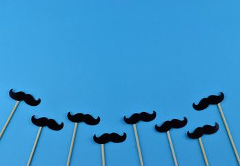Black mustaches on light blue background representing an annual event involving the growing of...