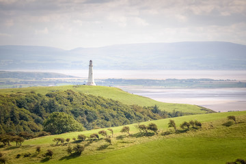 White lighthouse sanding tall on the English coast in the green landscape