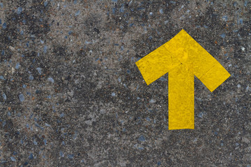 D.I.Y. yellow up arrow symbol builds by pike leak seal tape shown on old concrete floor of the walk...