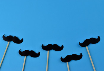 Black mustaches on light blue background representing an annual event involving the growing of...