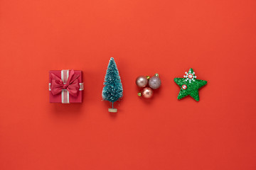 Table top view of Merry Christmas decorations & Happy new year ornaments concept.Flat lay essential object the fir tree & gift box bauble with star on red paper background at studio office desk.