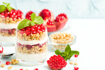 Pomegranate parfait - sweet organic layered dessert with granola flakes, yogurt and ripe fruit seeds.