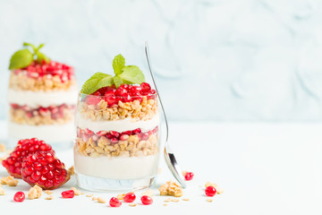 Pomegranate parfait - sweet organic layered dessert with granola flakes, yogurt and ripe fruit seeds.