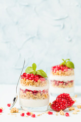 Pomegranate parfait - sweet organic layered dessert with granola flakes, yogurt and ripe fruit seeds.