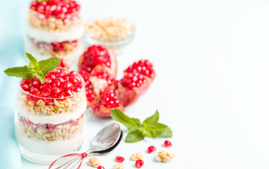 Pomegranate parfait - sweet organic layered dessert with granola flakes, yogurt and ripe fruit seeds.