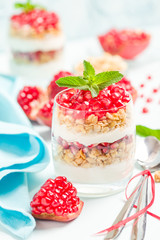 Pomegranate parfait - sweet organic layered dessert with granola flakes, yogurt and red ripe fruit seeds.