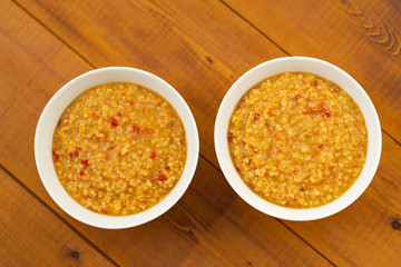 Turkish lentil bulgur soup sprinkled with pepper in a white bowl on a wooden background