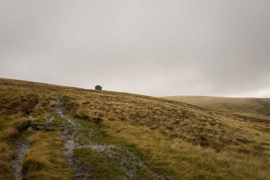 Wet hike through the Lake District of England with shelter in the distance and gray overcast