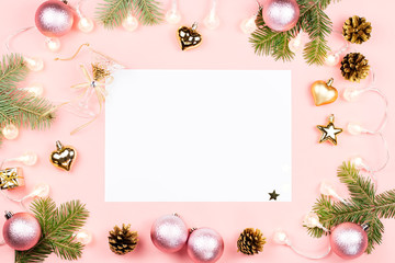 Christmas background with fir branches, lights, red giftboxes, pink decorations on pink, copy space