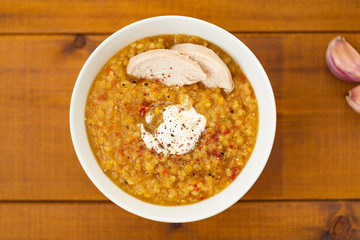 Turkish lentil bulgur soup sprinkled with pepper in a white bowl on a wooden background