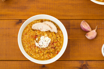 Turkish lentil bulgur soup sprinkled with pepper in a white bowl on a wooden background