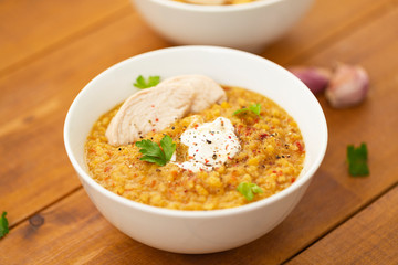 Turkish lentil bulgur soup sprinkled with pepper in a white bowl on a wooden background