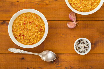 Turkish lentil bulgur soup sprinkled with pepper in a white bowl on a wooden background