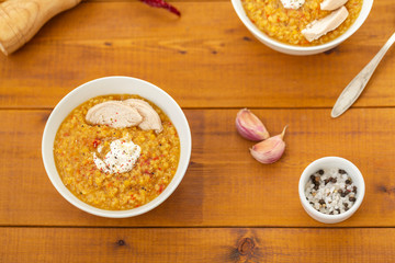 Turkish lentil bulgur soup sprinkled with pepper in a white bowl on a wooden background
