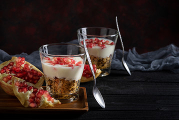 Granola with yogurt and pomegranate on black wooden table