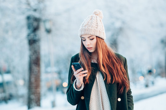 Young  woman smiling with smart phone and winter landscape .