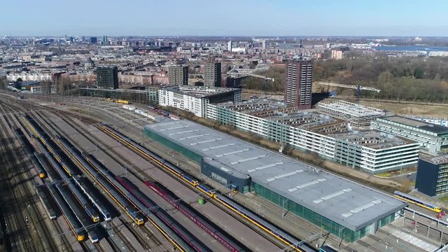 Aerial footage of train maintenance station showing passenger trains parked next to each other and the modern service building behind the permanent way beautiful blue sky day 4k high resolution