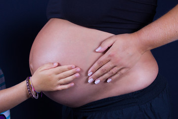Babybauch mit H&auml;nden von Mutter und Schwester