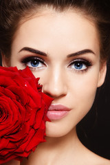 Close-up portrait of young beautiful woman with cat eye make-up and red rose