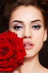 Close-up portrait of young beautiful woman with cat eye make-up and red rose