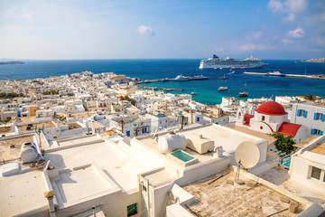 Panoramic view over Mykonos town with white architecture and cruise liner in port in Greece