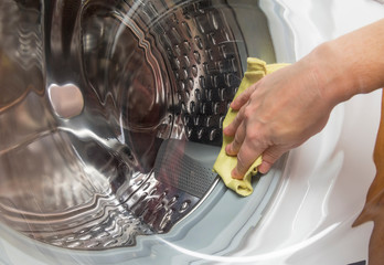 The girl washes with a cloth the glass washing machine.