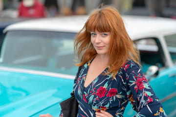 Ginger girl posing in front of a vintage blue car