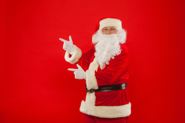Santa Claus pointing in blank a place, red background