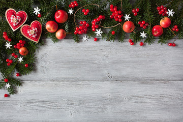 Fototapeta na wymiar Christmas wooden background with fir branches, hearts, red apples and berries
