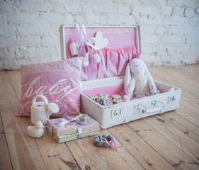 Fototapeta na wymiar White suitcase with pink decor and baby girl theme