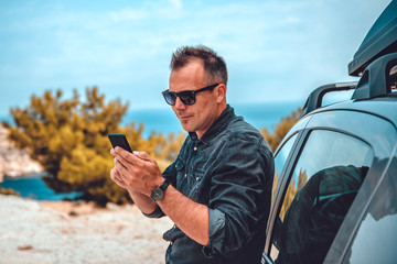 Man lean on car using smart phone