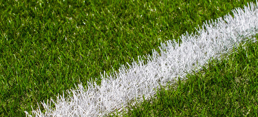 Green synthetic grass soccer sports field with white stripe line