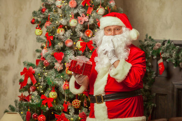 Santa Claus with giftbox on background of sparkling firtree