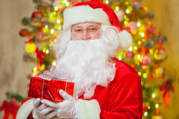 Santa Claus with giftbox on background of sparkling firtree