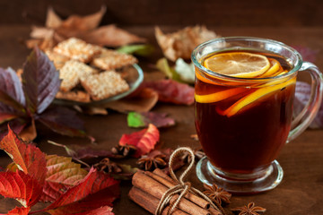 A cup of hot tea on the background of autumn foliage