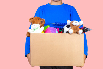 Donation concept. Kid holding donate box with clothes, books and toys