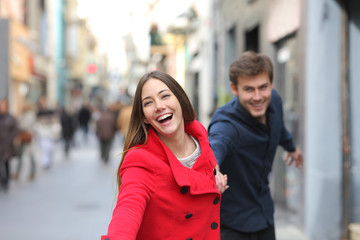 Happy couple running together in the street in winter