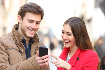 Couple checking phone content in winter in the street