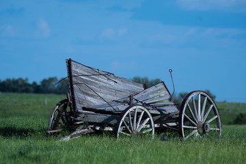 Fototapeta na wymiar Old Wooden Wagon Sitting in a Prairie Field 
