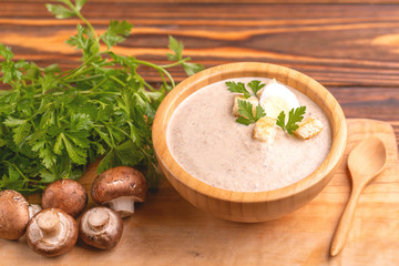 Tasty pureed mushroom soup in wooden bowl with ingredients