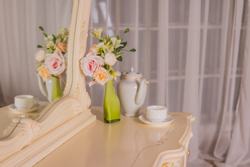 Fototapeta na wymiar Boudoir table. Details of the interior of the bedroom for girls and make-up, hairstyles with a mirror. Good morning coffee in bed.Boudoir table, dressing table.Romantic design for bedroom.