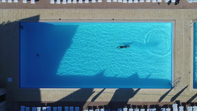 Young man swimming in a pool from an aerial perspective 