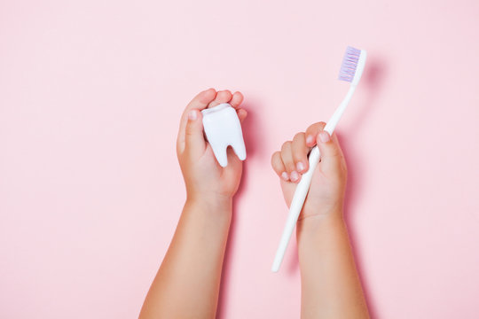 Child's Hands Holding Big Tooth And Toothbrush