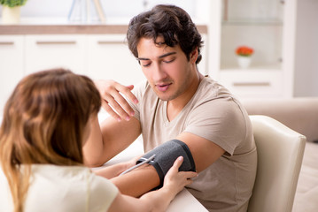 Wife checking husband's blood pressure  