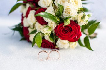Wedding rings and colorful bouquet on the snow
