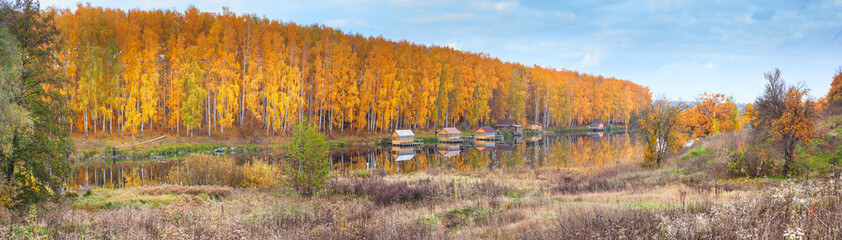 Autumn landscape - resting places on the shore of lake against the background of birch forest