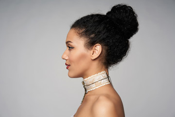 Beauty closeup profile portrait of beautiful mixed race caucasian - african american woman wearing chocker looking forward, isolated on gray background